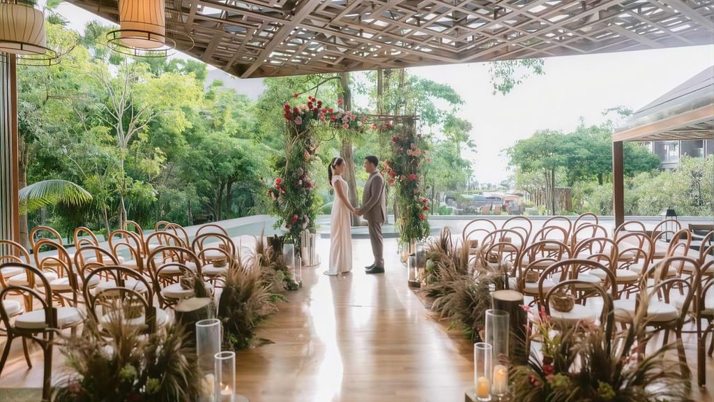 Couple holding hands beneath a floral wedding arch at an elegant open-air wedding venue surrounded by tropical greenery.